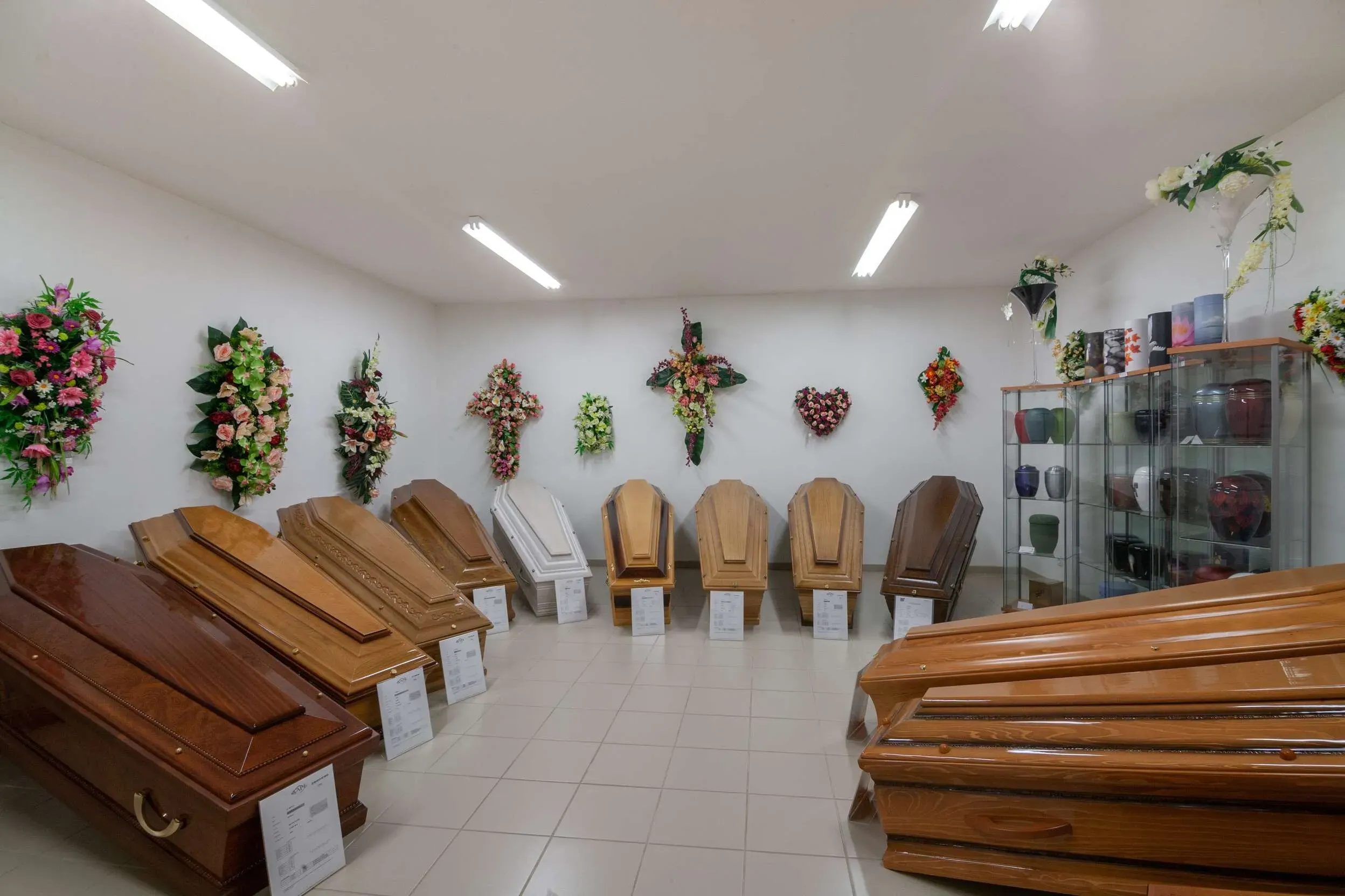 Salle d'exposition présentant une sélection de cercueils en bois et urnes.